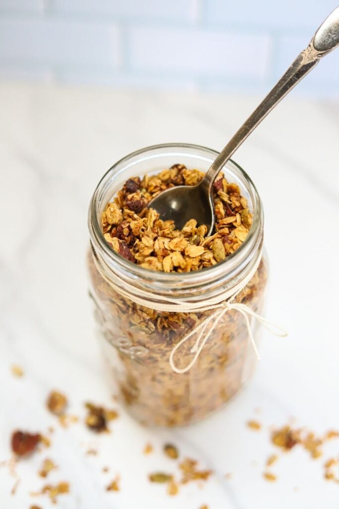 Homemade pumpkin spice granola in a glass jar with fall flowers