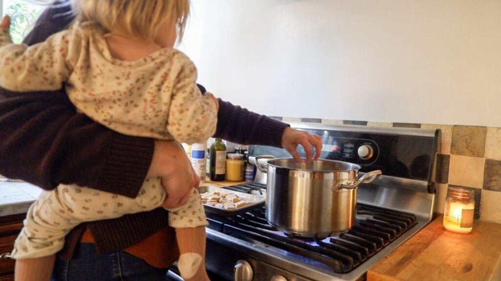 11. Cooking pumpkin gnocchi in a pot while holding a baby.
