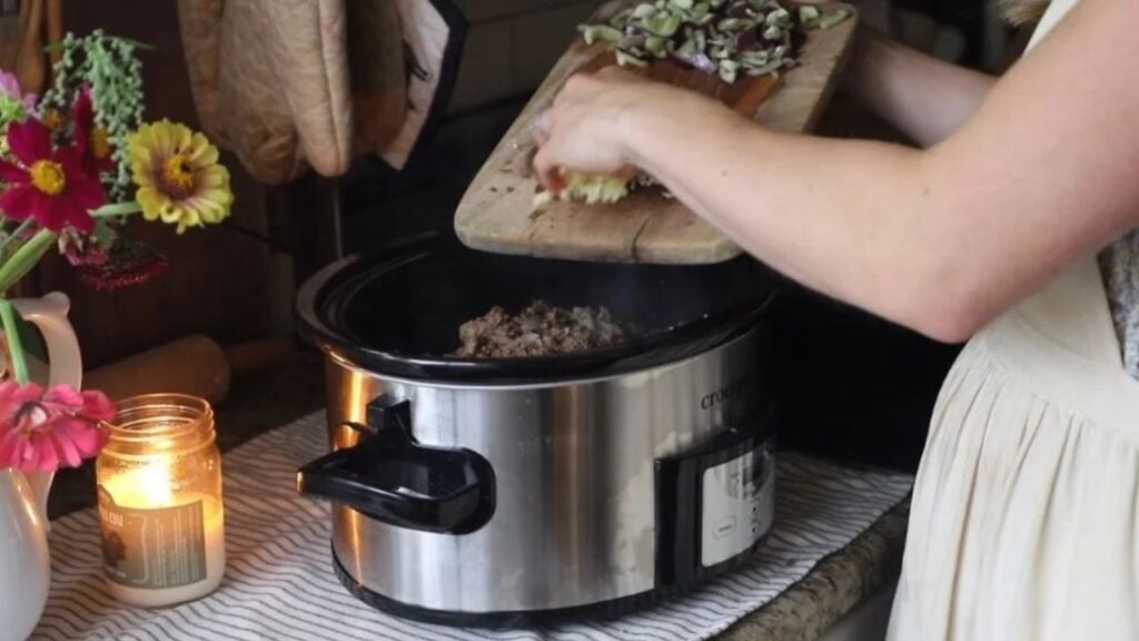 Stainless steel slow cooker filled with a homemade meal in a cozy kitchen.