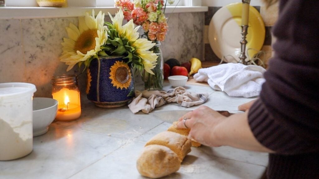 Flattening pumpkin gnocchi dough on a kitchen counter.